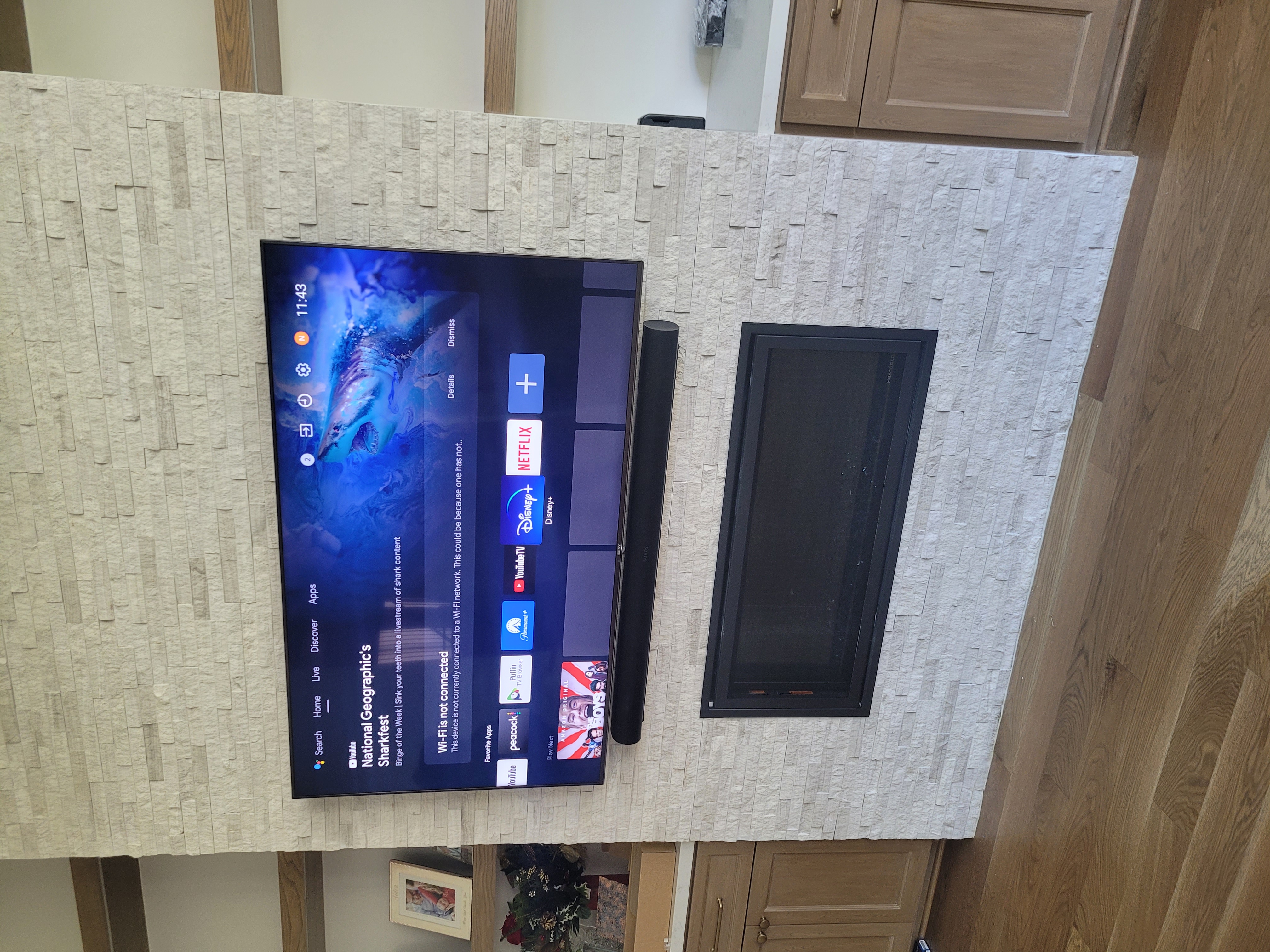 TV and soundbar mounted above stacked ledger stone fireplace wall