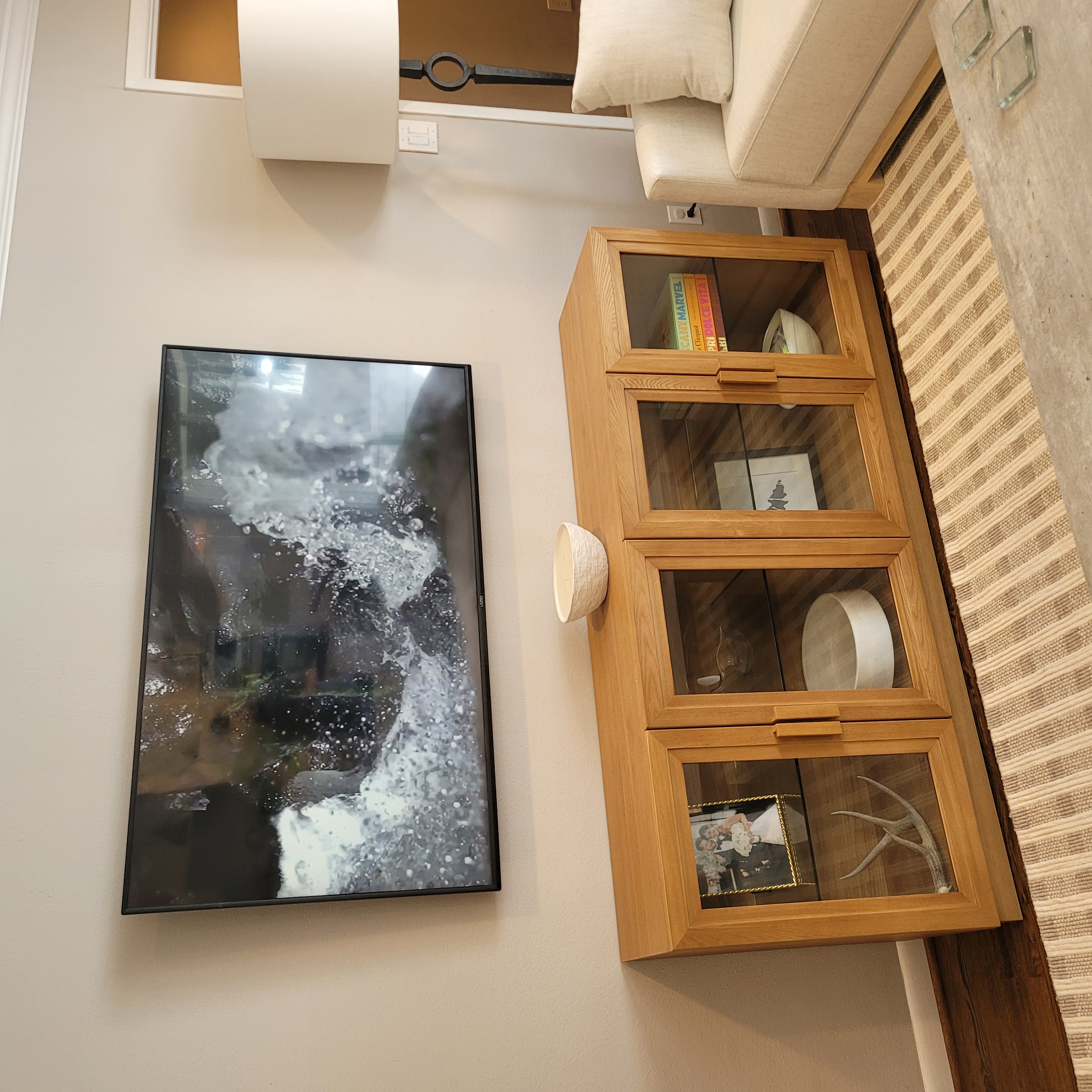 TV wall-mounted above oak media console in bright Houston living room